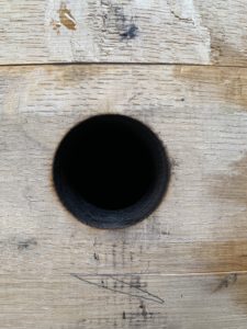 Close up image of a blackened hole in the side of a wooden barrel