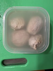 Four pale, round testicles half-float in a container of briny liquid