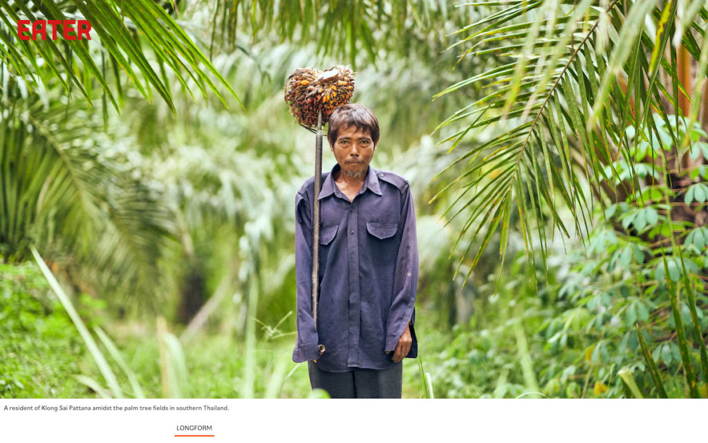 Screenshot of the top of the Eater article, featuring Eater's logo and a photo of a middle-aged Southeast Asian man holding a bunch of oil palm fruit at the end of a stick, staring straight into the camera against a verdant backdrop of palm trees.